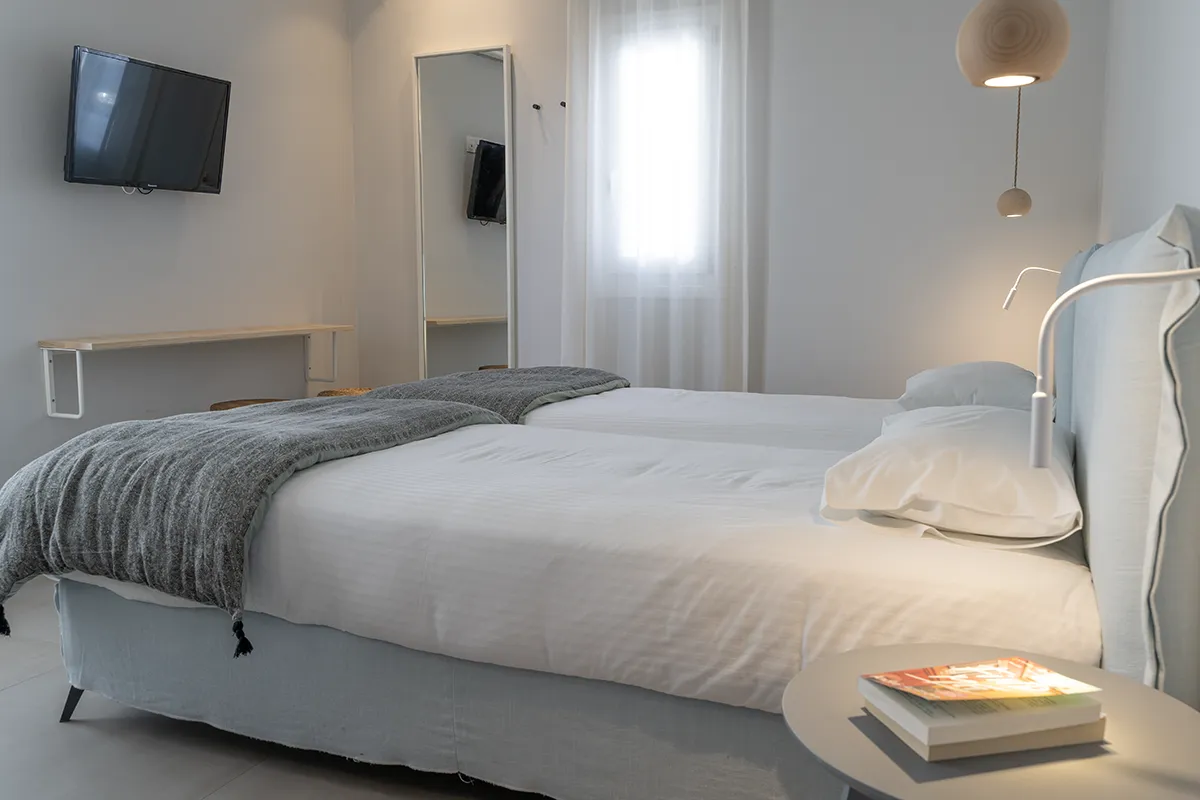 A minimalistic hotel room in white and soft grey.
